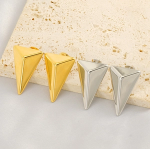 Macro view of minimalist 18K gold and silver triangular stud earrings on stone