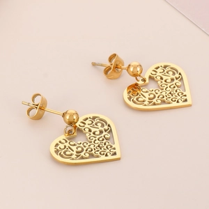 Close-up of gold heart stud earrings featuring intricate hollow scrollwork pattern