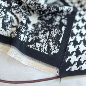 Detailed close-up of houndstooth scarf texture with soft fringe and ink painting patterns