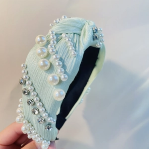 Detail eines mintgrünen Knotenstirnbands mit Perlen und Strass auf Satinstoff