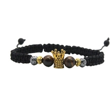 Detailed shot of black braided bracelet with golden crown and natural tiger eye stones