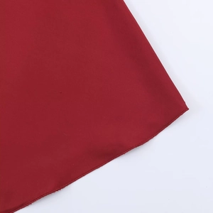 Dettaglio della texture del tessuto in raso rosso scuro e cuciture dell'orlo di qualità
