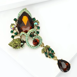 Detail of vintage gold flower brooch with amber and green teardrop glass rhinestones