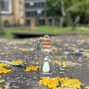 Macro shot of the ghost charm in a glass drift bottle pendant on a silver metal chain