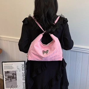 Pink satin hobo bag with metallic butterfly charm shown on model in a minimalist setting