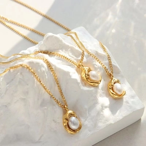 Gold-plated Cuban chain necklace featuring natural baroque pearls on a textured white base
