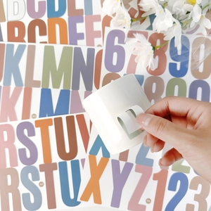 Applying colorful vinyl letter U sticker to a white ceramic mug for DIY decoration