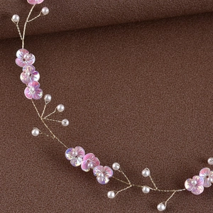 Close-up of handmade bridal headband with pink flowers and pearls on gold wire