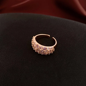 Macro detail of rose gold open ring featuring three rows of pavé-set pink crystals