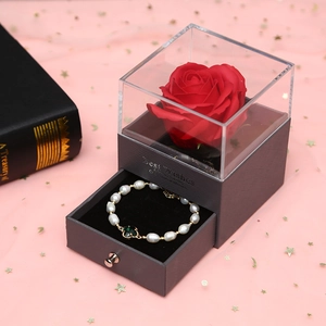 Detail of red soap rose and clover pearl bracelet in a gray acrylic jewelry gift box