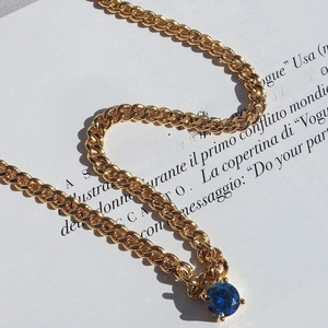 Detail of 18k gold plated Cuban chain with a claw-set blue round zircon pendant
