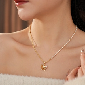 Detailed view of a gold necklace featuring a pearl chain and winged unicorn pendant