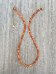 Detailaufnahme der orangefarbenen Naturstein-Halskette mit vergoldetem Verschluss und Kette