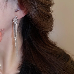 Elegant side view of long tassel heart earrings with shimmering rhinestones on a model