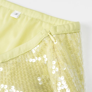 Détail de la taille d'une jupe à paillettes jaune clair avec fermeture éclair et étiquette S