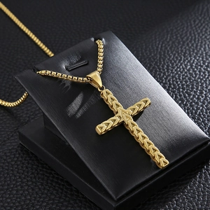 Close-up of golden cross pendant with wheat grain texture on black leather background