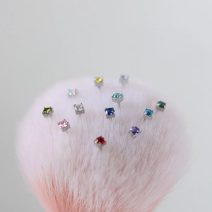 Close-up of colorful round-cut birthstone stud earrings in silver four-claw settings