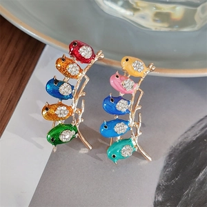 Macro shot of gold enamel bird brooch on a branch with sparkling crystal rhinestones