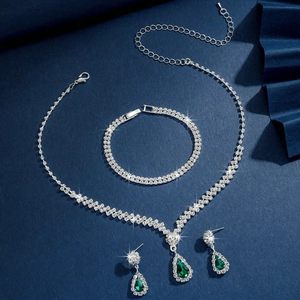 Gros plan sur l'ensemble de bijoux de mariée argentés avec pierres vert émeraude et zircons