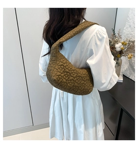 Close-up of floral quilted texture on army green puffy shoulder bag worn with a white dress