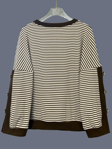 Dettaglio del top in maglia a righe con bottoni dorati decorativi sulle maniche e polsini