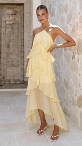 Detail of multi-layered yellow chiffon tiered dress with high-low hem and halter neck