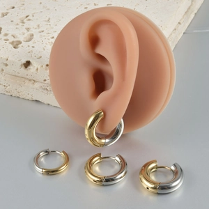 Detail showing two-tone gold and silver stainless steel hoop earrings on a display ear model