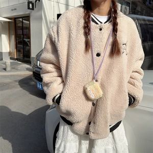 Dettaglio della texture in pile sulla giacca varsity color albicocca con polsini a righe