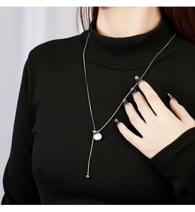 Detail of adjustable silver snake chain with baroque pearl on black turtleneck