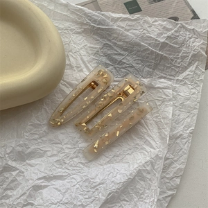 Close-up of cream resin hair clips set with gold foil flakes and metal base