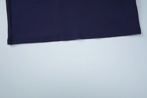 Detailed macro view showing dark blue ribbed knit fabric texture and hem stitching quality