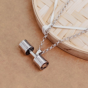 Silver dumbbell necklace pendant with FIT 10KG engraving for fitness lovers on bamboo tray