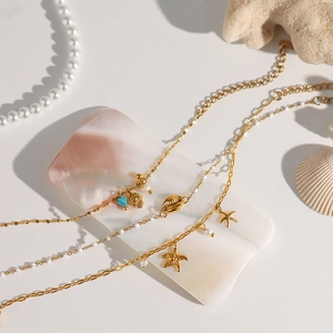 Detail of gold ocean bracelet with starfish, pearls and turquoise heart charms