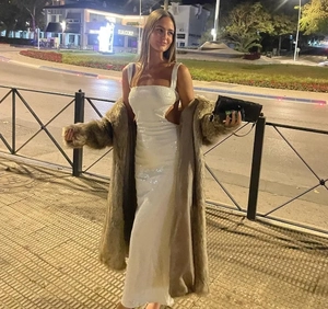 Detail of a white sequin evening dress paired with a luxurious brown faux fur coat outdoors