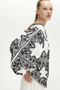 Détail d'une veste blanche décontractée avec broderies noires et design effet miroir