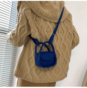 Mini sac à bandoulière bleu sur un mannequin portant un pull en maille beige de dos