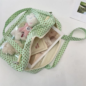 Detail view of transparent PVC tote bag featuring green polka dots and storage space