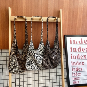 Detailed display of leopard print canvas hobo bags in different patterns hanging on wood