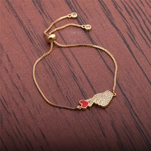 Detail of adjustable gold-plated heart palm bracelet with red enamel on wood