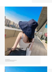 Deep blue wide-brim sun hat shown from behind on a model against a city sky background