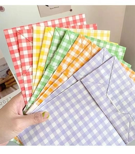 Hand holding a set of colorful checkered gift paper bags with serrated edges for packaging