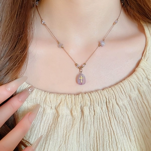 Détail du collier de perles violettes et pendentif croix dorée sur un mannequin