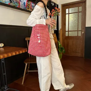 Close-up of red and white gingham plaid tote bag with a white side label on fabric