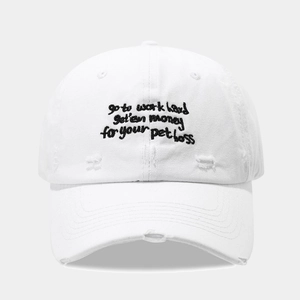 Close-up of white distressed baseball cap with black embroidered lettering and ripped details