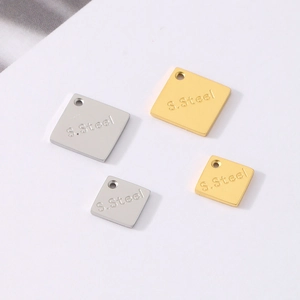 Macro shot of gold and silver square stainless steel charms with S.Steel engraving