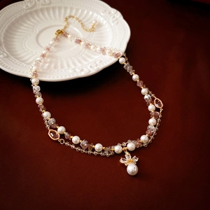 Detail of double-layer necklace with pearls, purple crystals and floral pendant