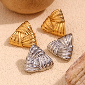 Macro view of gold and silver triangular earrings with textured striped metal surface