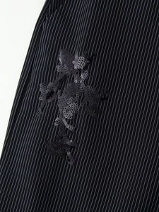 Détail du tissu noir à rayures avec broderie de paillettes florales sur la veste