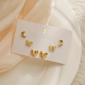 Three pairs of 18K gold plated heart moon and butterfly stud earrings on a display card