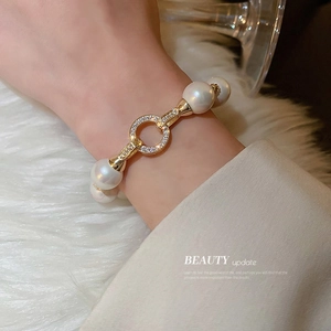 Elegant gold-plated pearl bracelet with zircon encrusted ring clasp worn on wrist